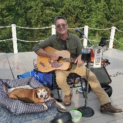 man playing guitar and beagle dog
